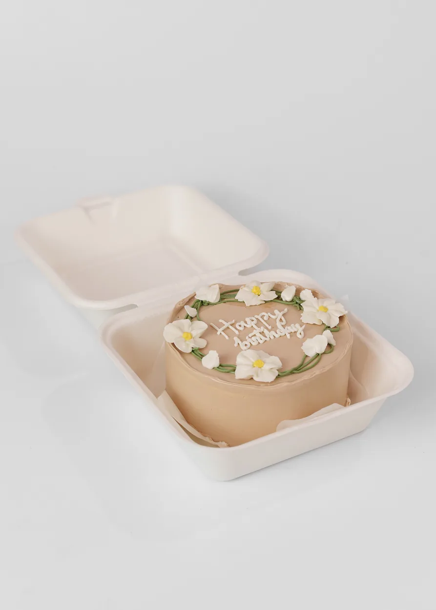 Bentô cake bege com flores brancas e folhas verdes em buttercream